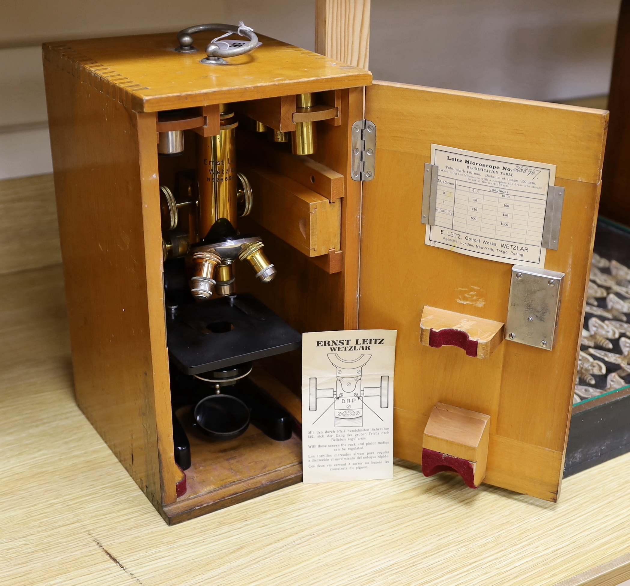 An early 20th century Leitz microscope in a teak case, with alternative lenses, card inserts and sliding compartment with glass slides, matching serial numbers stamped onto case and on magnification table